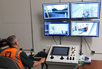 A new vision system will allow remote-handling operators to view and record work taking place. The operator is sitting next to a control unit that allows for remote operating of a crane.  The crane uses guides to direct the magnet in and out of the beam-accelerating cryomodule.