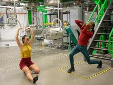 Performers from Dance Exchange dance in front of scientific equipment at FRIB.